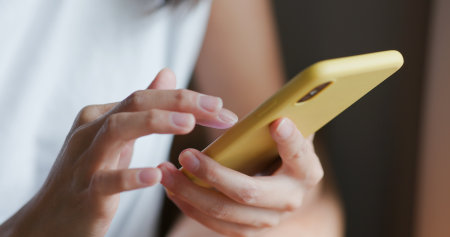 Close up of woman use of mobile phone at homeの写真素材