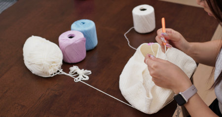 Woman hand knitting white yarn at home