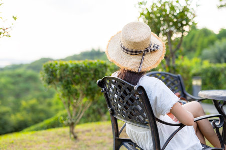 Woman sit on outdoor chair and look outsideの写真素材
