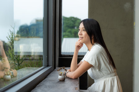 Woman look outside the view of the window in coffee shopの写真素材