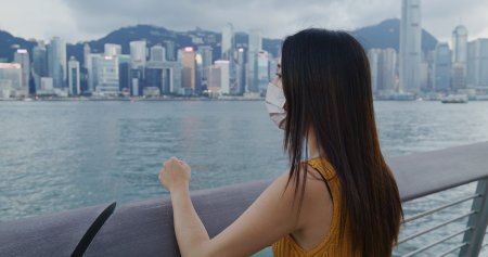 Woman wear face mask and look at the Hong Kong city