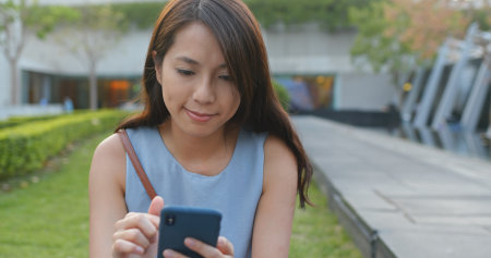 Woman using smart phone in the parkの写真素材