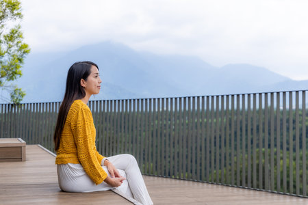 Woman sit on the wooden deck to view the scenery mountainの写真素材