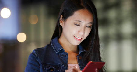 Woman send sms on cellphone at nightの写真素材