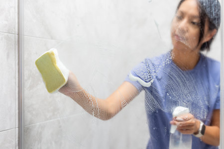 Woman remove hard water stains and deposits in bathroomの写真素材
