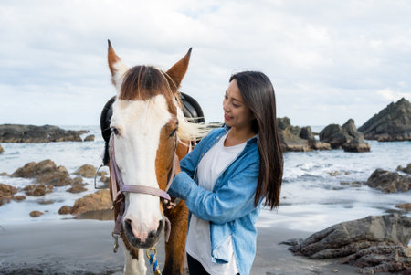 Tourist woman cuddled a horse at the sea beach