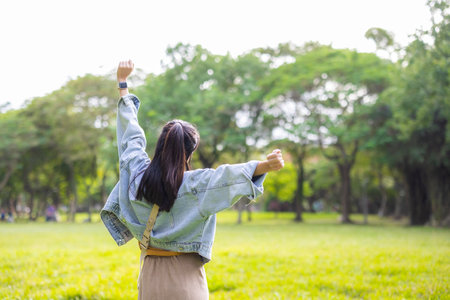 Asian woman stretching hands up in parkの写真素材