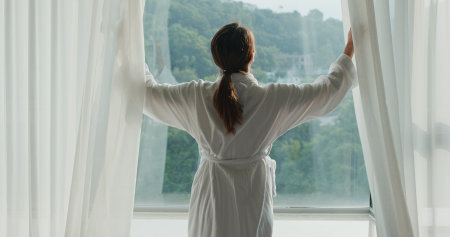 Woman open curtain at homeの写真素材