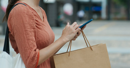 Woman using mobile phone with shopping bagの写真素材