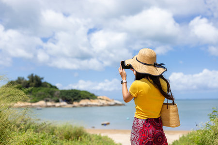 Woman use take photo on mobile phone in seasideの写真素材