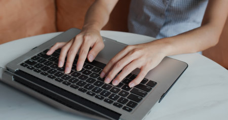 Woman types on laptop computer at homeの写真素材