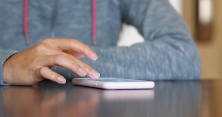 Woman use smart phone and sit on the tableの写真素材