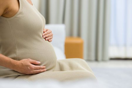 Pregnant woman hold with her tummy and sit on sofa at home