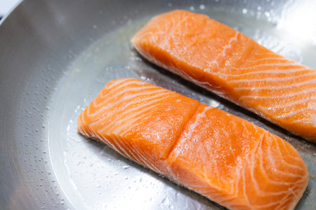 Fresh raw salmon fillets cooking on skilletの写真素材