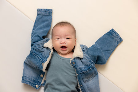 Adorable baby wearing oversized denim jacket indoors