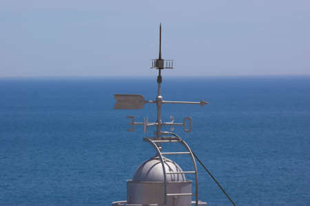 Weather vane on top of the lighthouse in Peniscola against blue sea.の写真素材