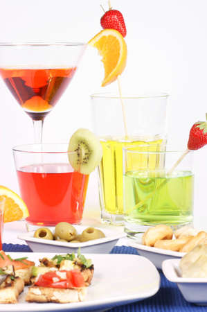 Italian bruschetta, taralli, artichokes and green olives served on white plates and colored aperitif drinks decorated with fresh fruit served in different drinking glasses. Studio shot. Selective focus, shallow DOF.の写真素材