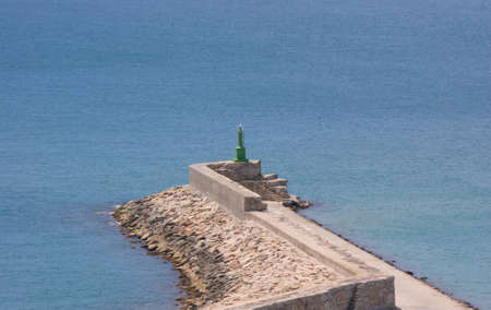 Small green lighthouse at seaport entrance in Peniscola (Valencia, Spain)の写真素材