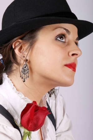 Portrait of a sexy young woman wearing a black hat and holding a red rose. Studio shot.の写真素材