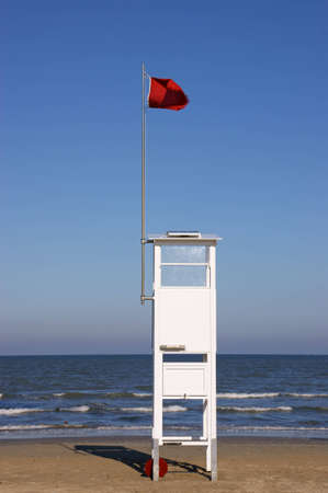 Lifeguard tower on the beach with a red warning flagの写真素材