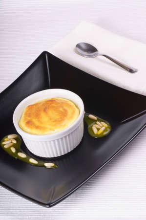 Lemon and ricotta souffle in a white ramekin over a black plate. Studio shot, shallow DOFの写真素材