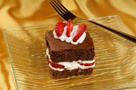 Fancy strawberry brownie with whipped cream served on a glass plateの写真素材