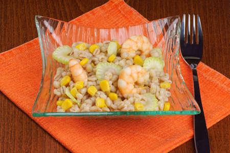 Pearl barley salad with shrimps, corn and celery served in a glass plate の写真素材