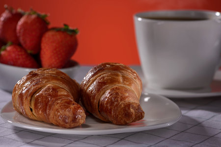 Croissants with coffee and strawberry on a red backgroundの写真素材