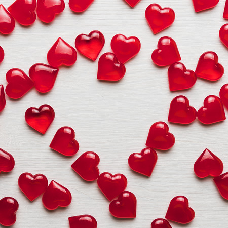 Background of red hearts on a white wooden substrate