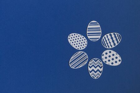 Easter eggs cut from paper on a classic blue background