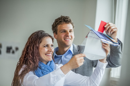 Smiling young business people choosing red color from swatches in officeの写真素材