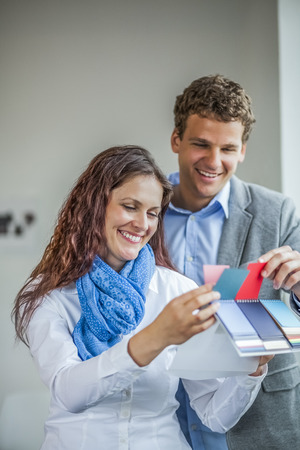 Smiling young business people choosing color from swatches in officeの写真素材