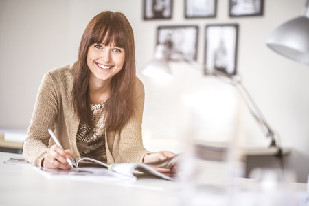Portrait of smiling young businesswoman working at desk in officeの写真素材