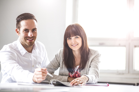 Portrait of young businessman and businesswoman discussing together in officeの写真素材