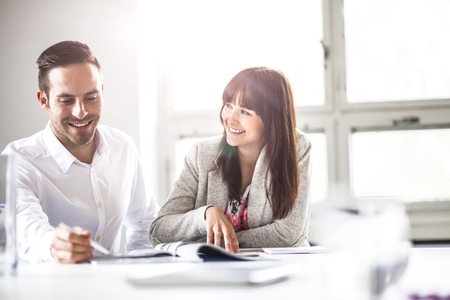 Smiling young business people discussing together in officeの写真素材