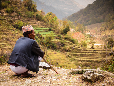 Nepal, March 2017: A local man dressed in traditional clothing looks out over a valley in the Annapurna region.のeditorial素材