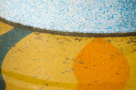 Water fountain almost empty of water and dirty with leaves and other rubbish. Pool tiles in the sun.の写真素材