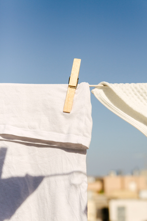 White clothes hung out to dry on a washing line in the bright warm sun. Background is a clear blue sky.の写真素材