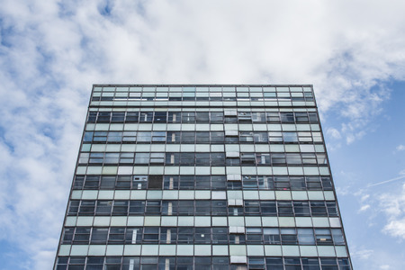 Grey and green office block facade against a blue sky with puffy clouds in London, United Kingdom