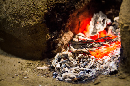 Embers of a dying fire in a wood fired stove made out of mud and clay in a traditional outdoor Sri Lankan kitchen.の写真素材