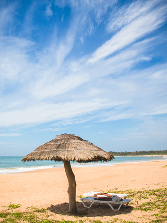 A straw umbrella and deckchair on kahandamodara beach, just outside of Tangalle, Sri Lanka.の写真素材