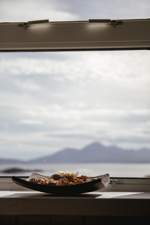 bowl of pot pourri with landscape in the background lit by the sun, portrait orientation