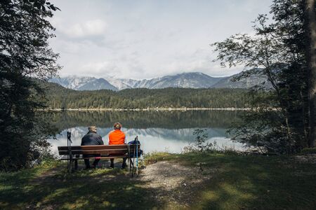 An elderly couple sit on a bench after walking round the lake. Eibsee, Garmisch-Partenkirchen, Bayern, Germanyの写真素材