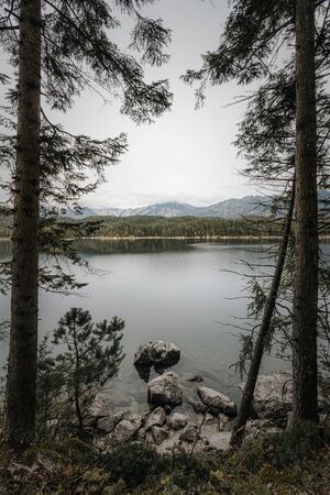 View of Eibsee lake, framed between two tall trees. Eibsee, Garmisch-Partenkirchen, Germany.