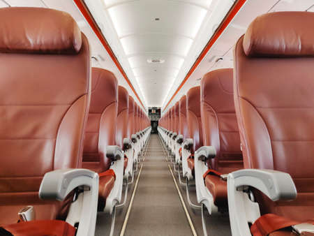 Empty interior cabin of an Airbus A320 Neo with red seats and trim. Many airlines face dire straits as they face a worldwide shutdown of travel due to Covid-19のeditorial素材