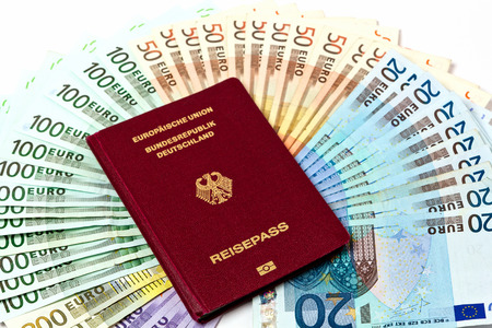 Different euro bills 500 200 100 50 Euro banknotes lying on a table. On top of the money lies a passport as a symbol for a journeyの写真素材