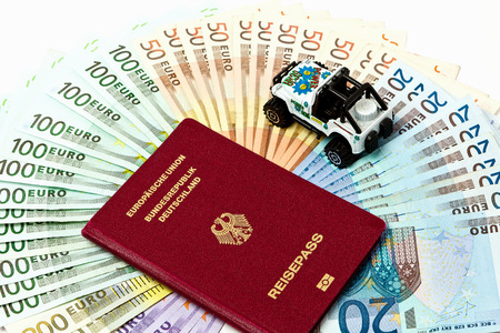 Different euro bills 500 200 100 50 Euro banknotes lying on a table. On top of the money lies a car and a passport as a symbol for a journeyの写真素材