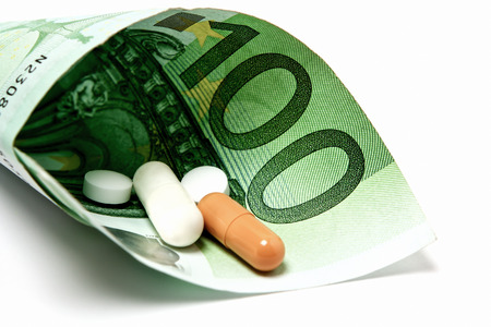 Medicine is nestled in a 100 euro note as a symbol of sick pay or medical moneyの写真素材