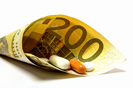 Medicine is wrapped in a 200 euro note as a symbol of sick pay or medical moneyの写真素材
