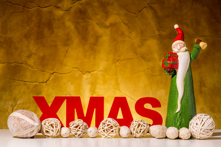 Red XMAS character on a brown background. Santa Claus is ringing  with a golden bell.の写真素材